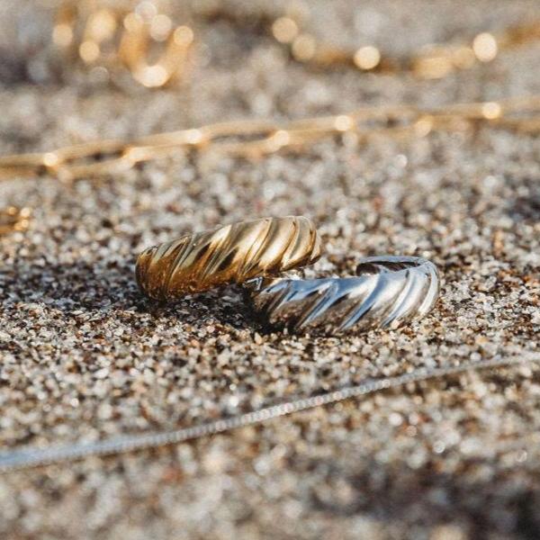 Crescent elegance open ring both in 18k gold plated and silver options picture on New Zealand beach.