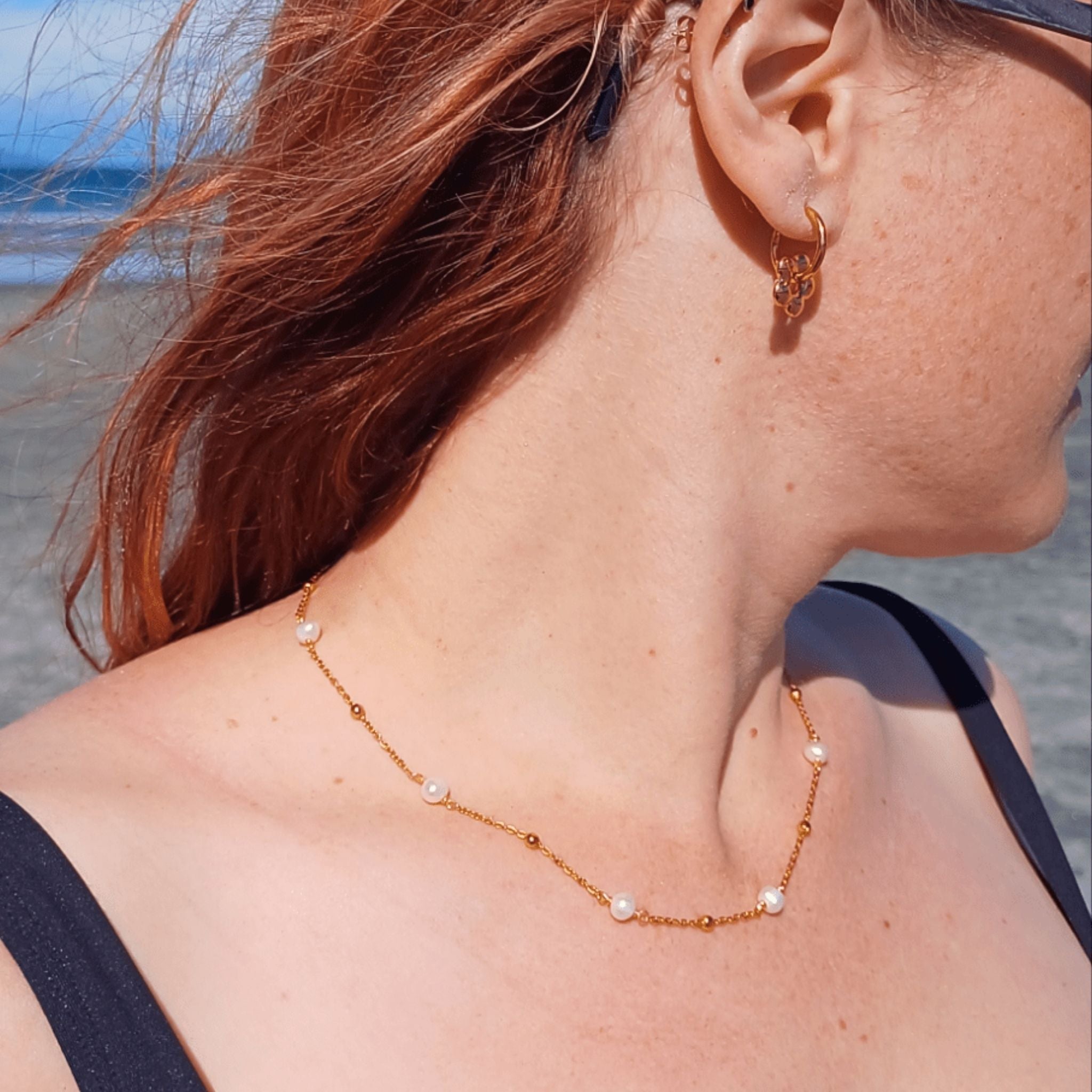 Standard-size woman wearing the 40cm Ocean Whispers Freshwater Pearl Necklace with 18K gold-plated chain and natural freshwater pearls, styled beautifully on the beach.
